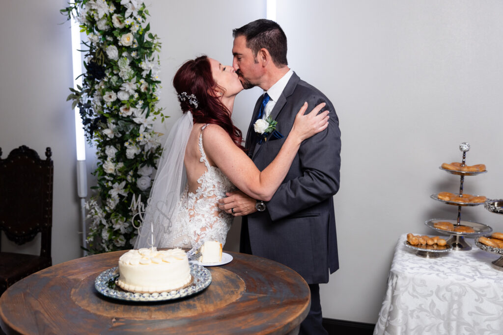 Bride and groom kissing behind wedding cake