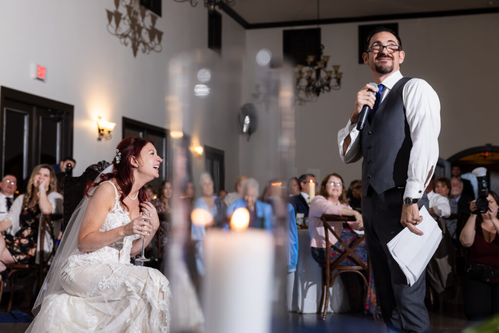 Bride laughing at groom during speech at wedding reception