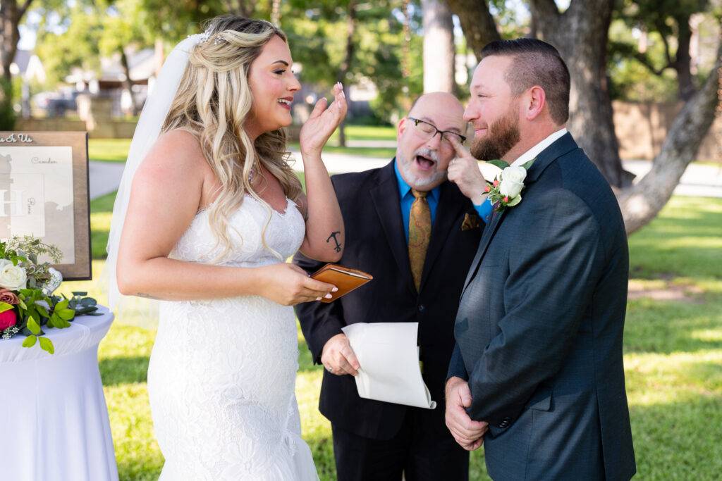 Bride and groom wiping tears from eyes and laughing during outdoor intimate elopement wedding ceremony in Granbury