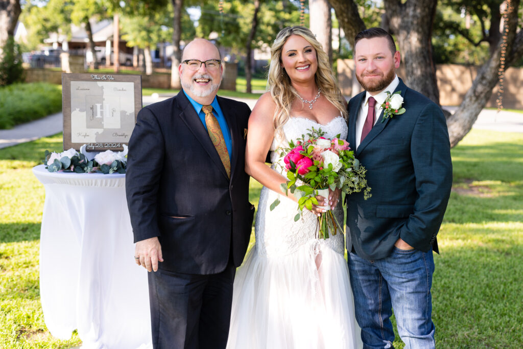 Bride, groom and officiant smiling at the camera after ceremony