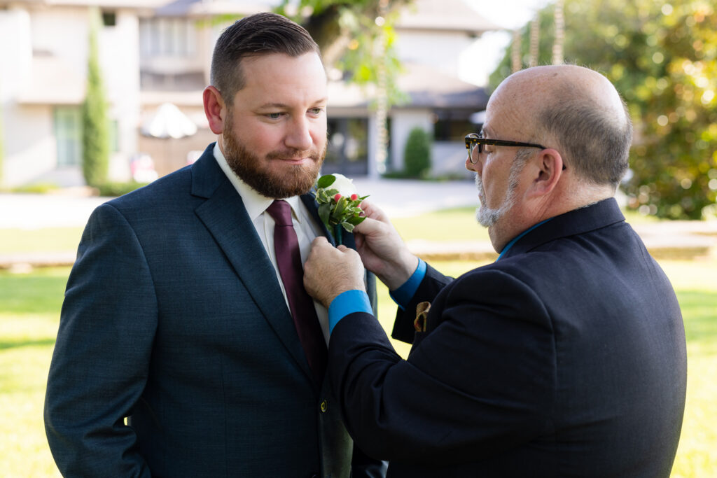 Officiant pinning boutonniere on groom