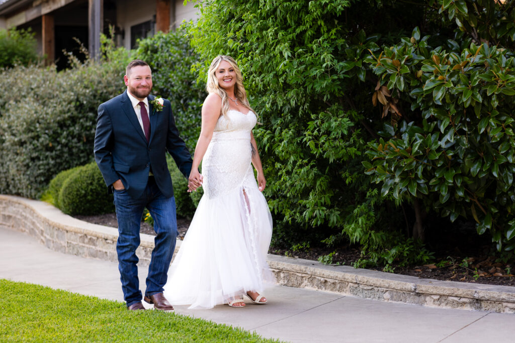 Wedding couple walking along path smiling ahead