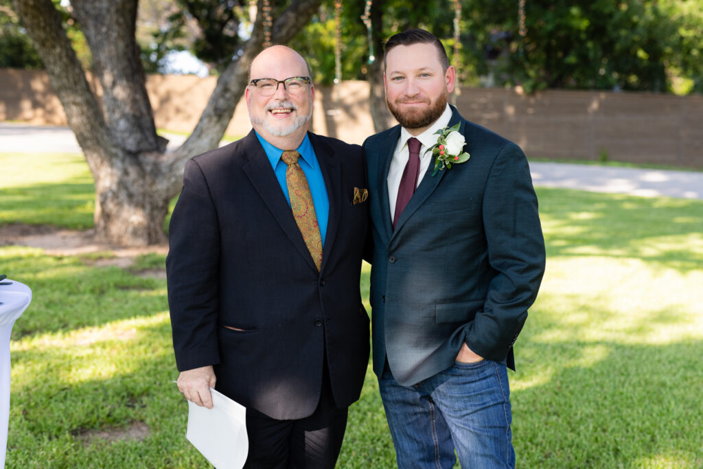 Groom and officiant hugging and smiling before wedding ceremony