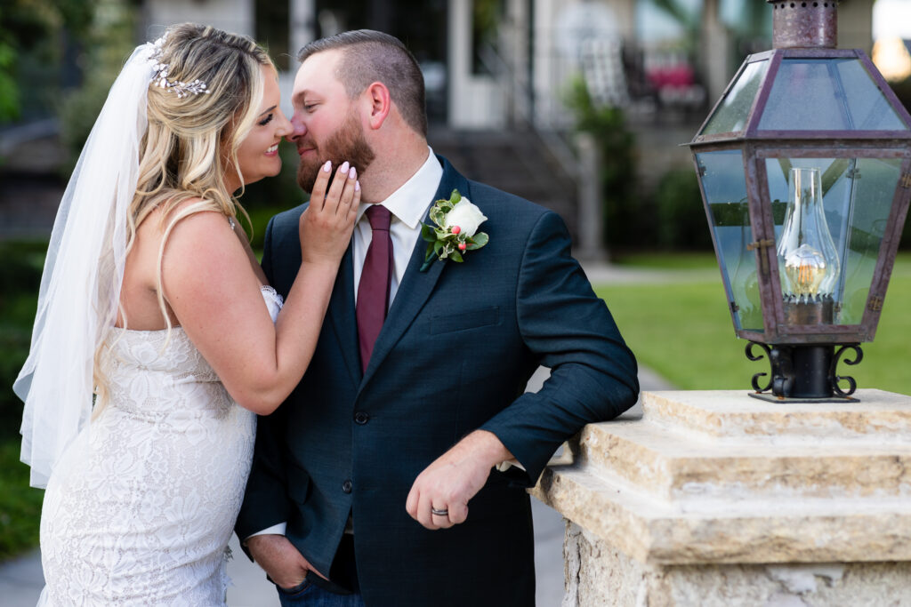 Groom leaning against light post while bride leans in for kiss