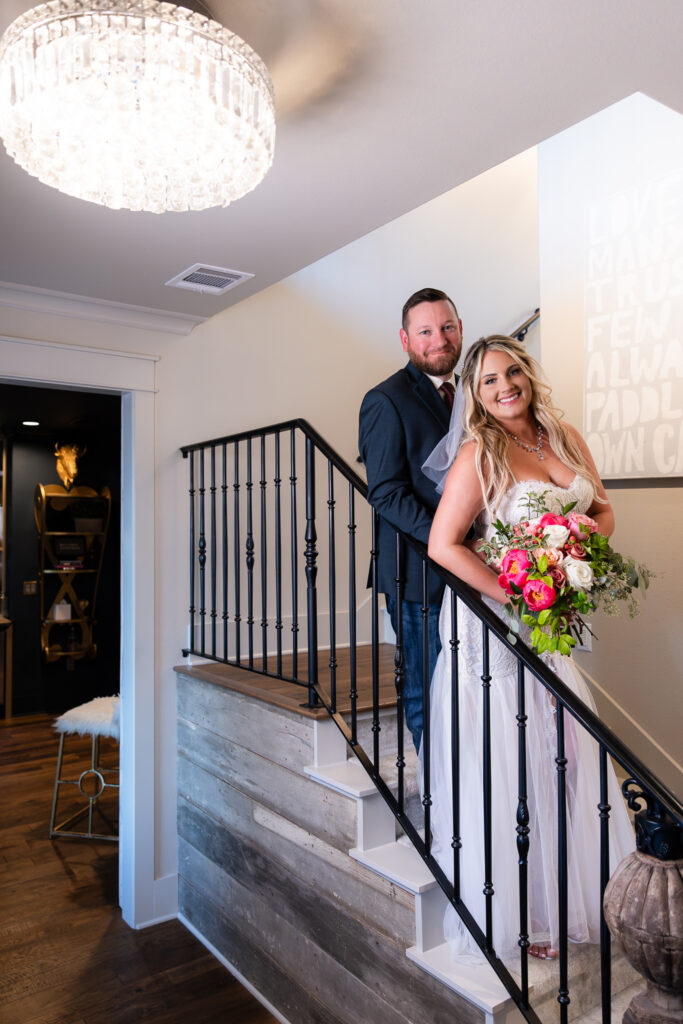 Bride and groom smiling against indoor staircase banister