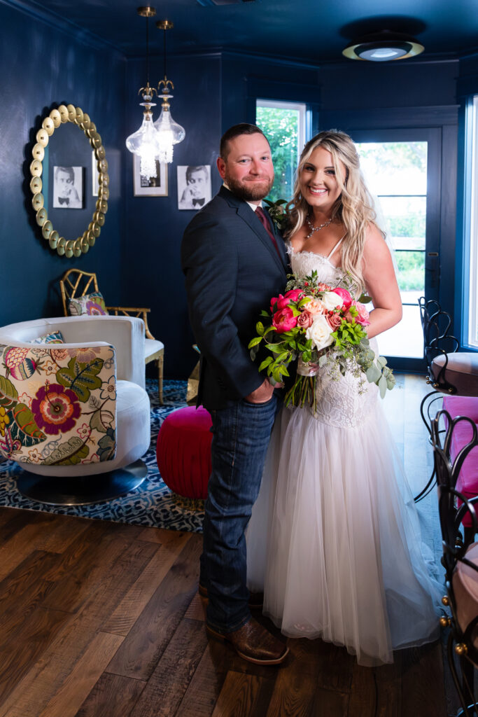 Bride holding pink flower wedding bouquet while standing next to groom inside Hotel Lucy bar