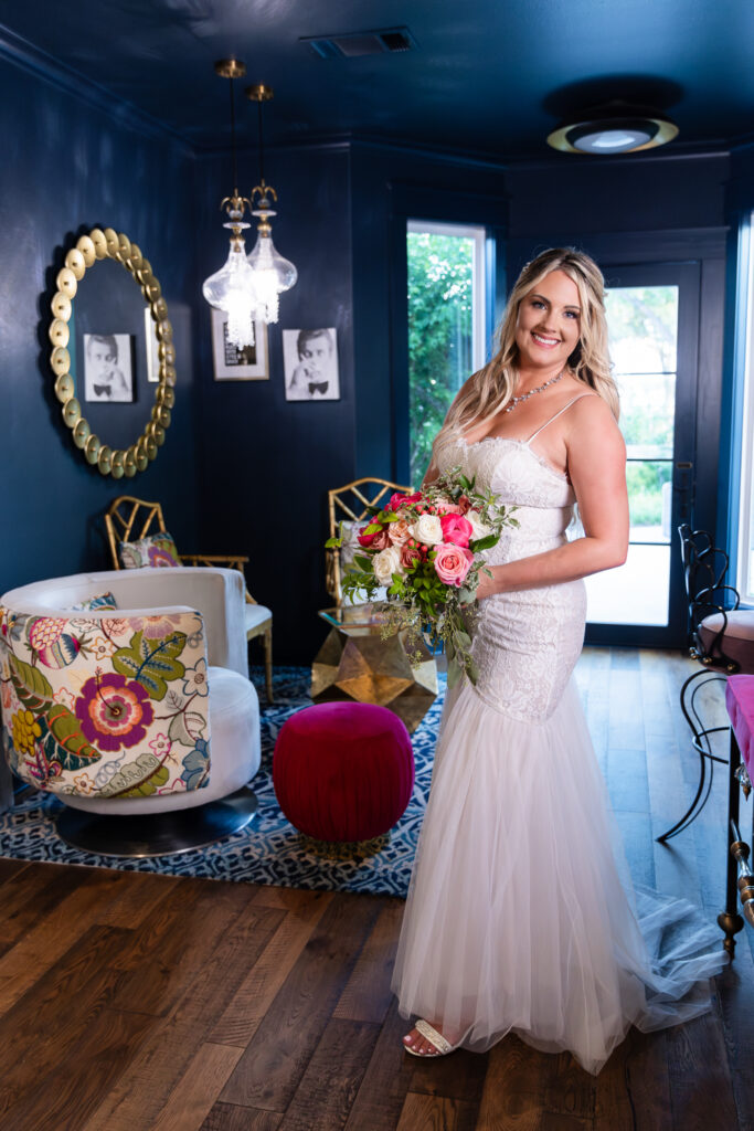 Bride holding pink flower wedding bouquet inside cute and chic blue hotel bar in Granbury TX