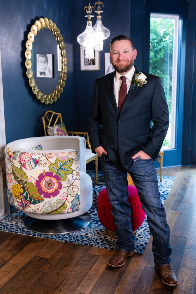 Groom standing inside chic blue hotel bar in Granbury TX