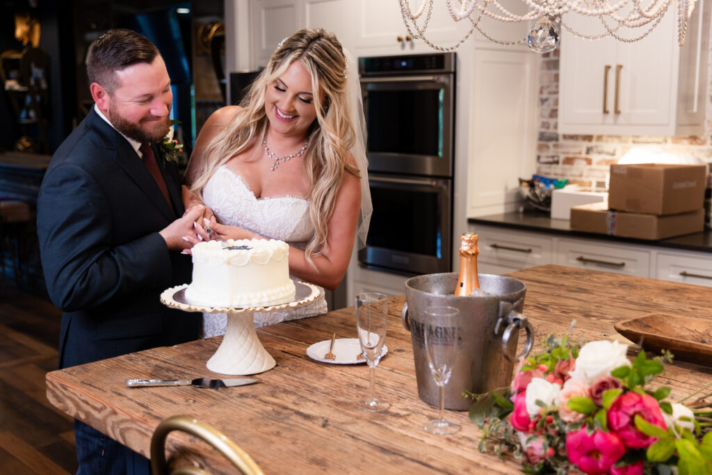 Bride and groom cutting simple heart shaped cake in Hotel Lucy's kitchen