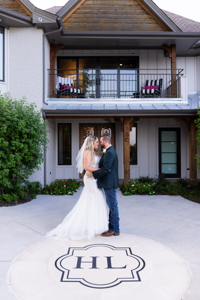 Bride and groom standing forehead to forehead in front of Hotel Lucy and their floor monogram