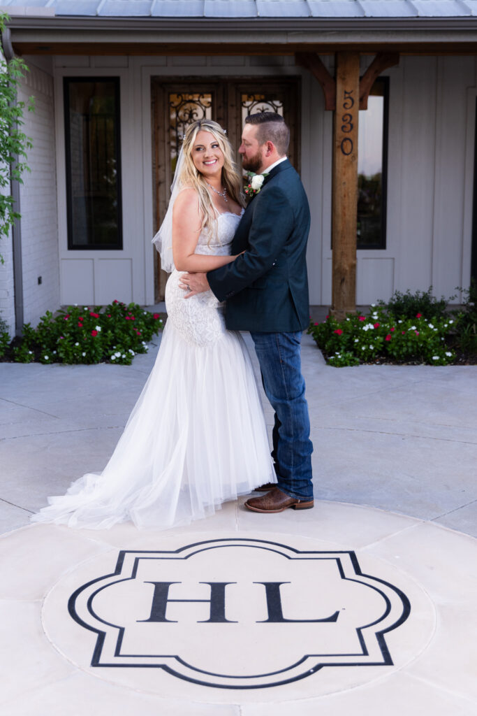 Bride and groom standing together smiling in front of Hotel Lucy and their floor monogram