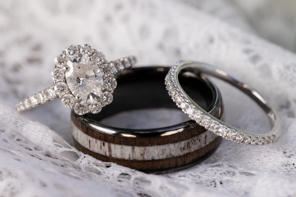 Diamond engagement ring, diamond wedding band and unique multi material wedding band against a lace backdrop