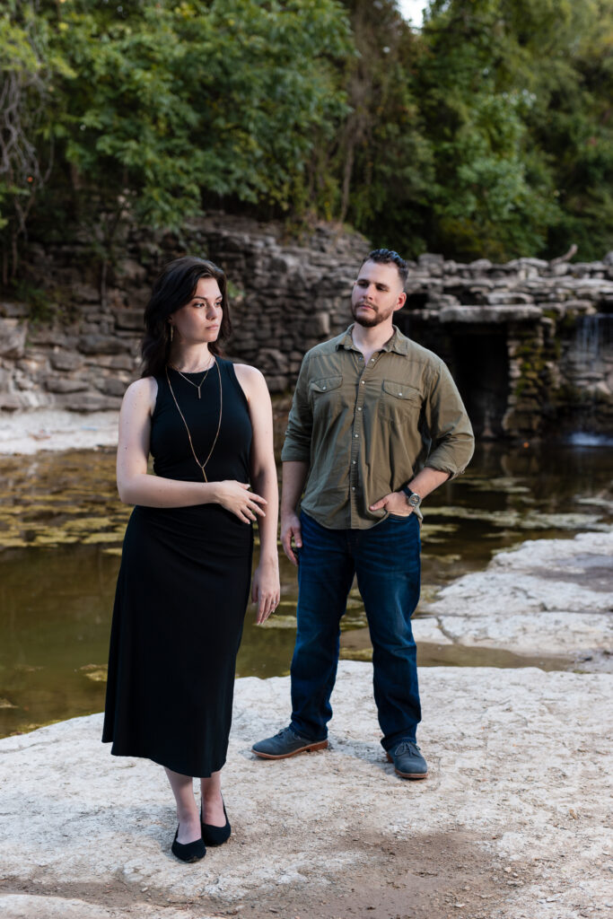 Engaged woman standing front of fiancé surrounded by epic stoned waterfall and lush greenery in Richardson TX