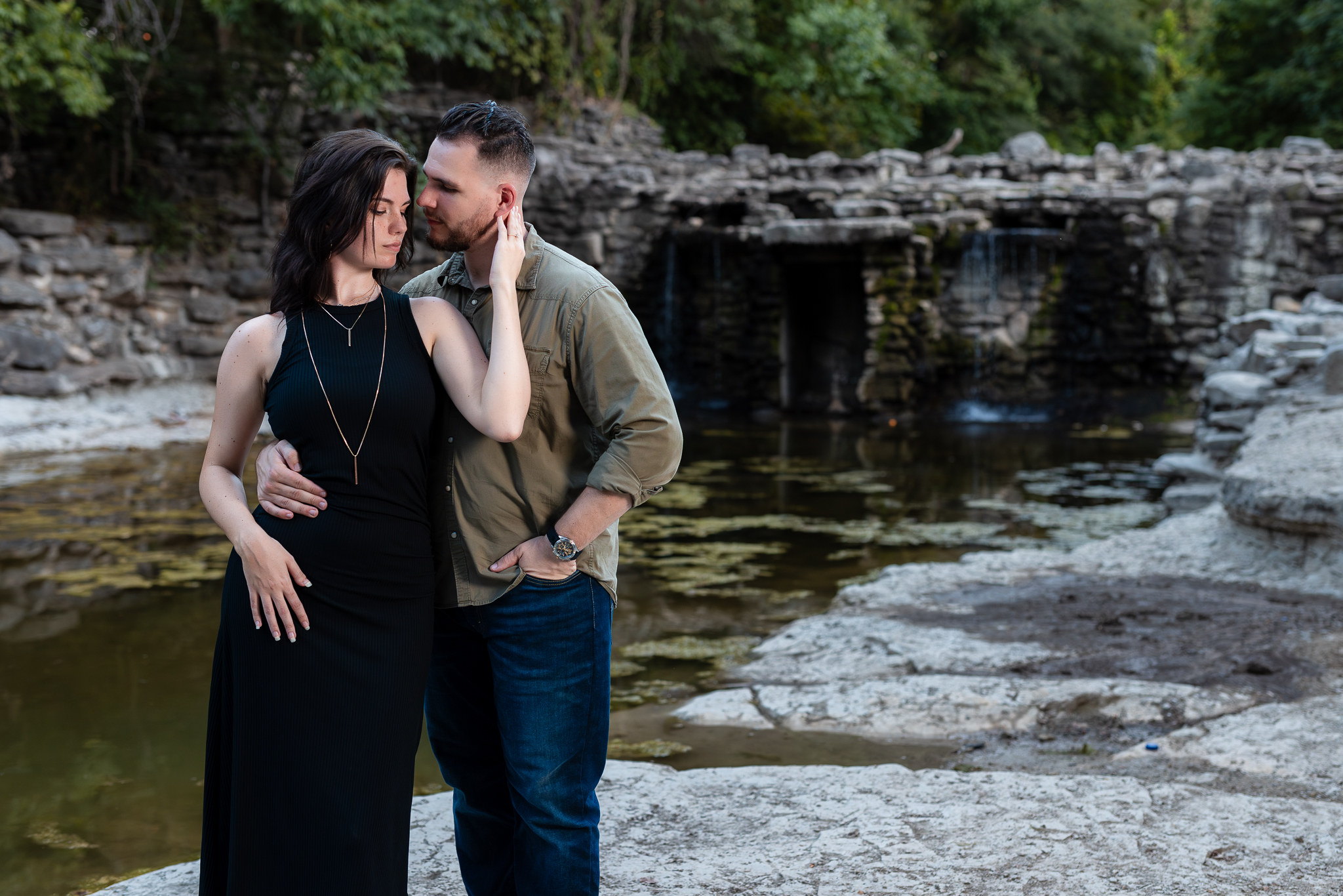 Engaged couple intimately snuggling in front of epic stoned waterfall in Richardson TX for engagement session