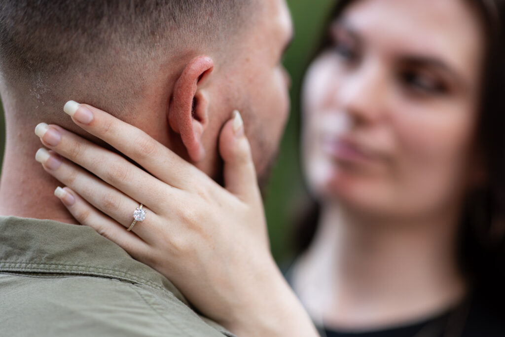 Close up of woman's hand with diamond engagement ring on fiancé's neck