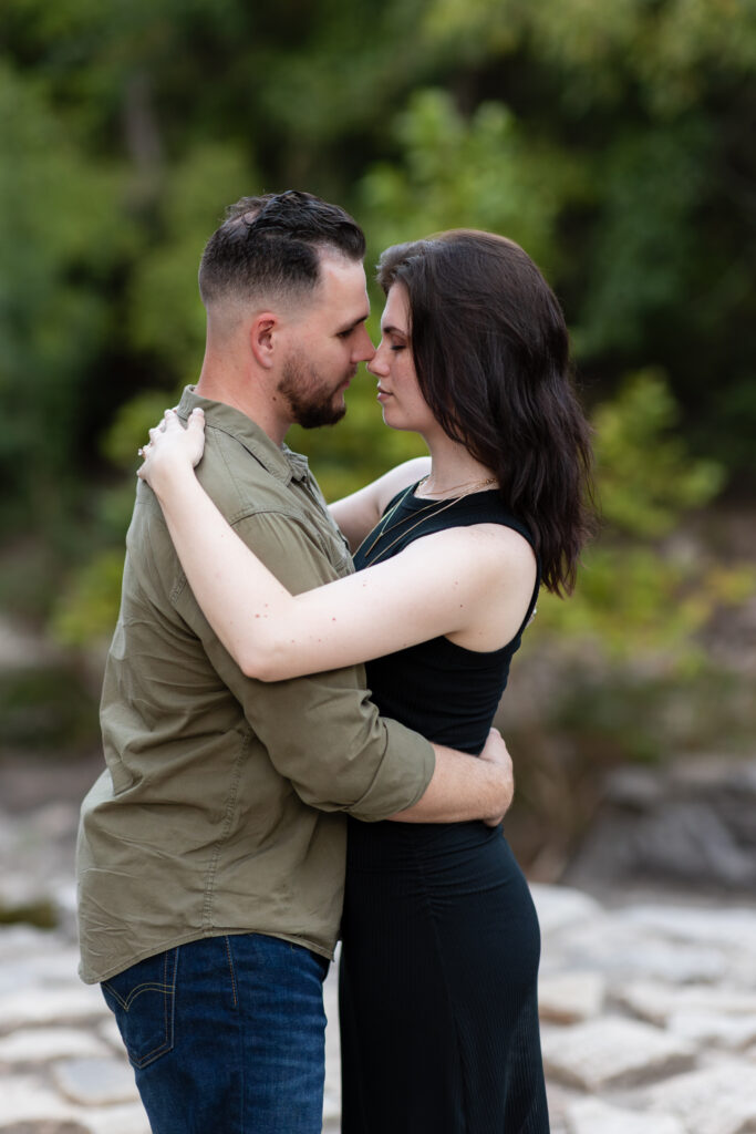 Engaged couple forehead to forehead and hugging during engagement session at a park in Richardson TX