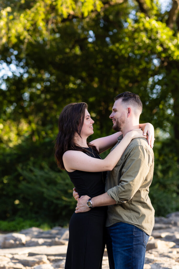 Engaged man and woman hugging and smiling at each other at lush Richardson Park engagement session