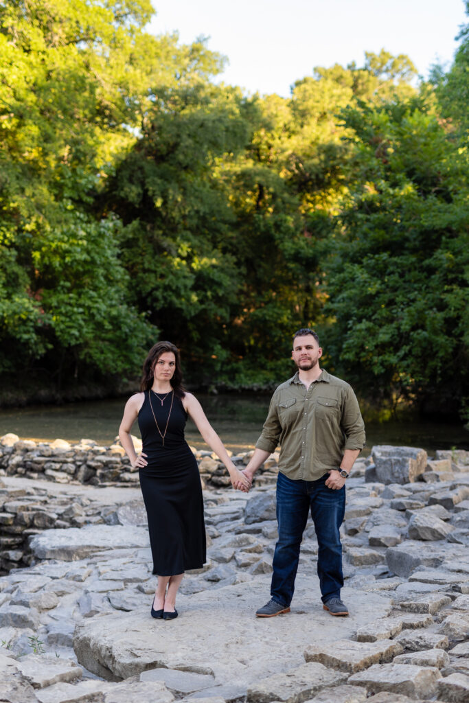 Engaged couple holding hands on stone pathway surrounded by wooded trees during beautiful Richardson Park engagement session