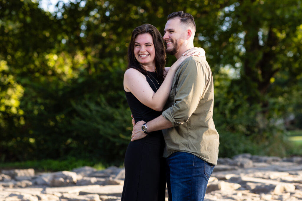 Man and woman hugging and laughing over her shoulder during lush Richardson Park engagement session