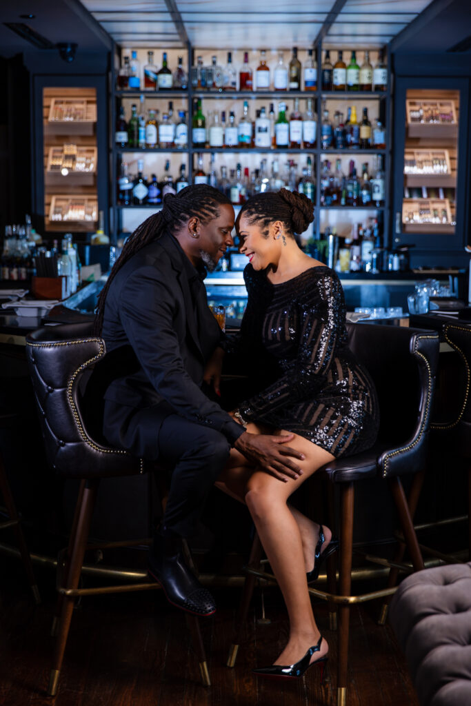 Married man and woman sitting on stools foreheads together at Thompsons Bookstore Speakeasy during anniversary session in FW