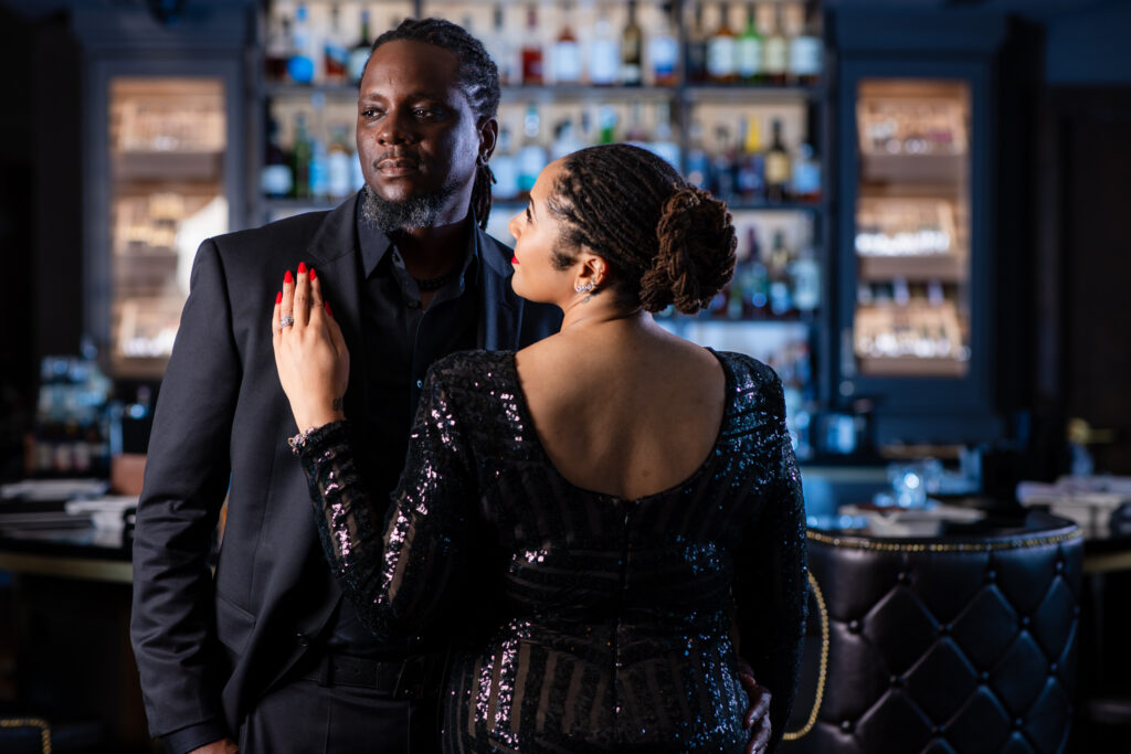 Woman leaning against man's chest in all black during anniversary portrait session at Thompsons Bookstore Speakeasy in downtown FW