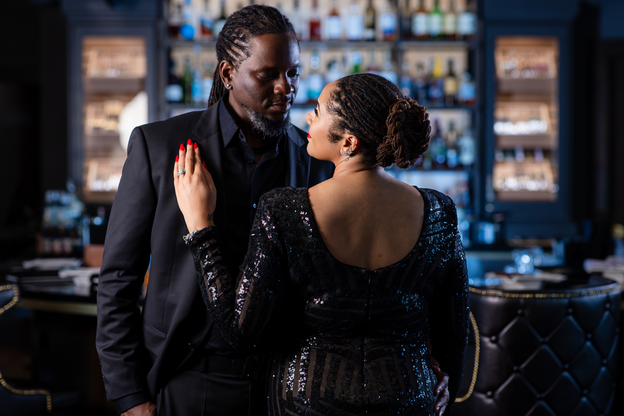 Woman leaning against man's chest in all black during chic anniversary portrait session at Thompsons Bookstore Speakeasy Fort Worth