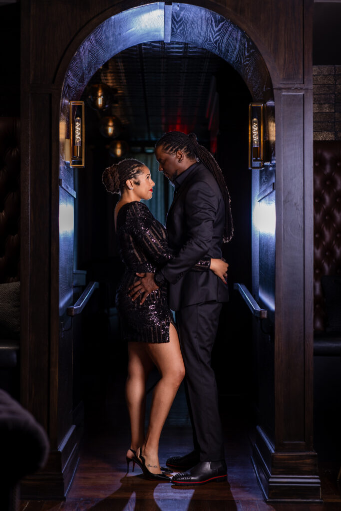 Man and woman standing forehead to forehead in archway in vintage Fort Worth speakeasy for a portrait session