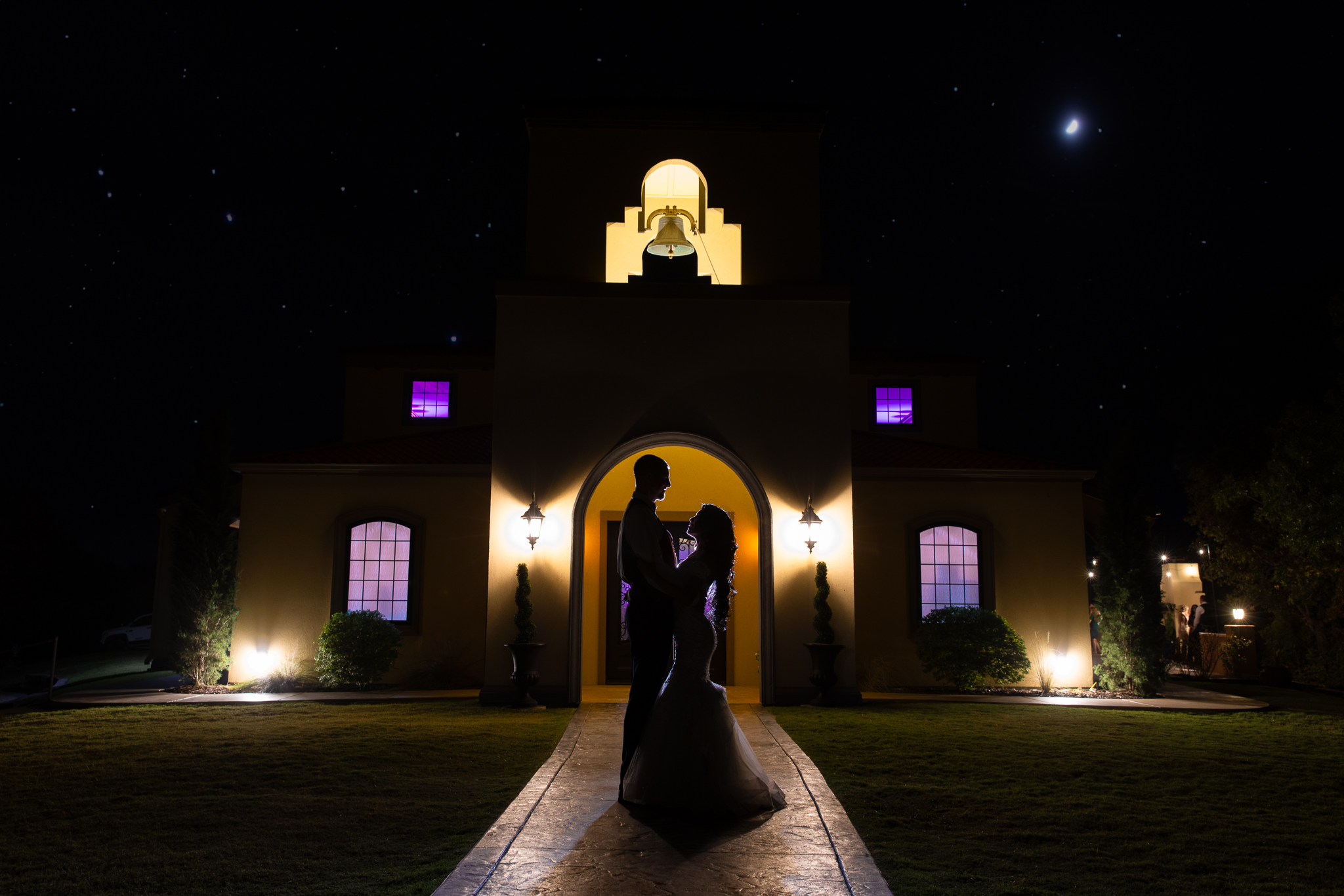 Silhouette photo of bride and groom in front of Stoney Ridge Villa's reception hall with bell tower at night with stars in the sky during Fort Worth Estate Wedding