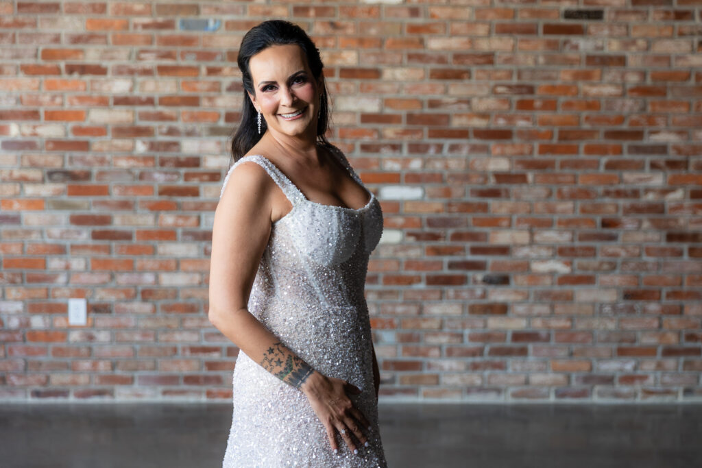 bride standing in front of brick wall in a Galia Lahav Oriana sparkling a-line wedding dress at Prosper Wine House in Prosper Texas