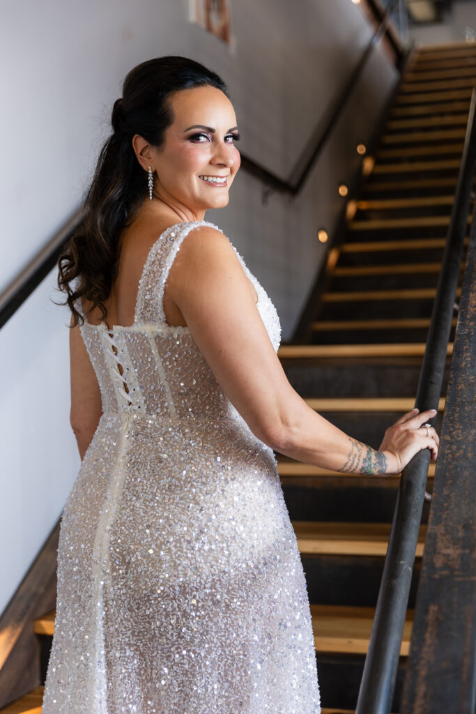 bride standing backwards on staircase in a Galia Lahav Oriana sparkling a-line wedding dress with a sweetheart neckline at Prosper Wine House in North Texas