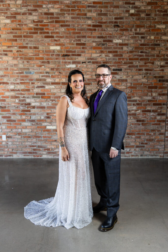 bride in a Galia Lahav Oriana sparkling a-line wedding dress smiling with groom in dark grey ted baker suit