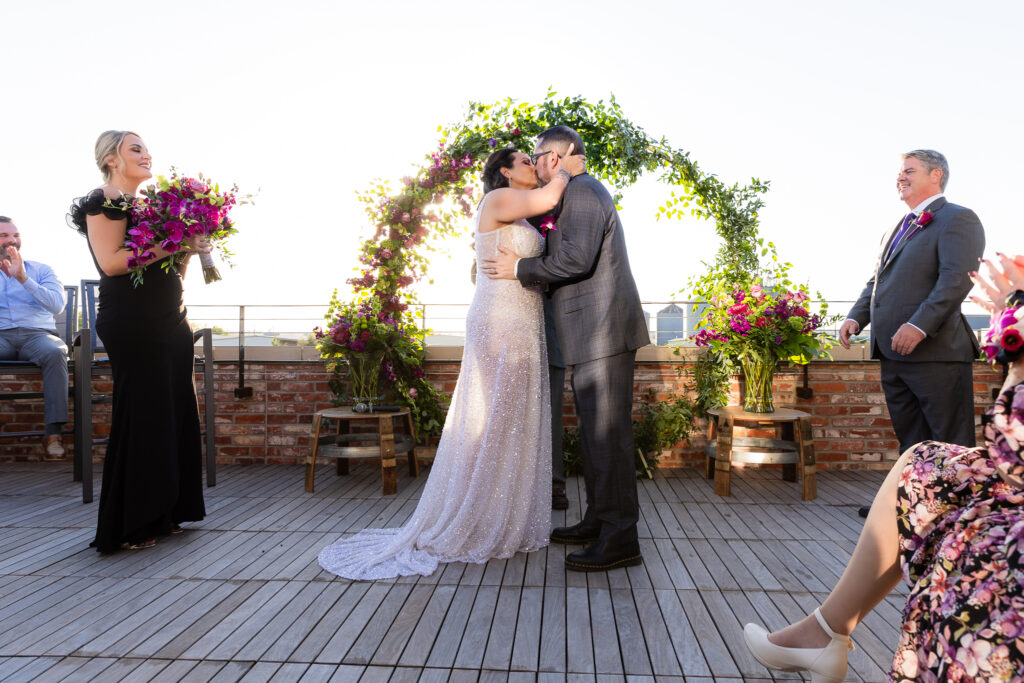 bridge and groom first kiss during rooftop ceremony at Prosper Wine House