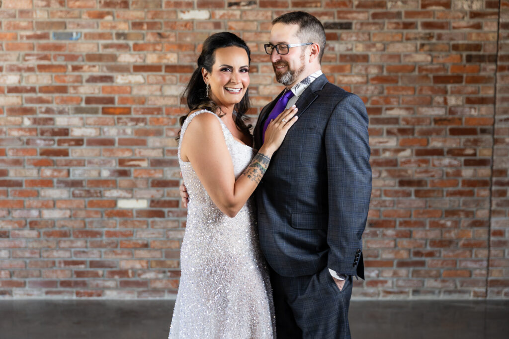 bride in a Galia Lahav Oriana sparkling a-line wedding dress smiling with groom in dark grey ted baker suit smiling at camera