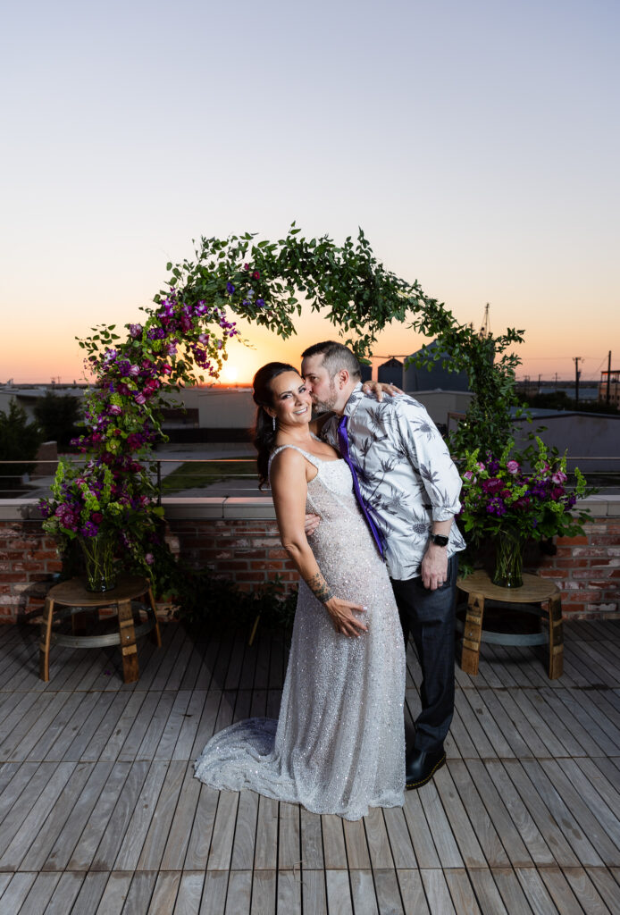 groom kissing and dipping bride on rooftop at Prosper Wine House at sunset