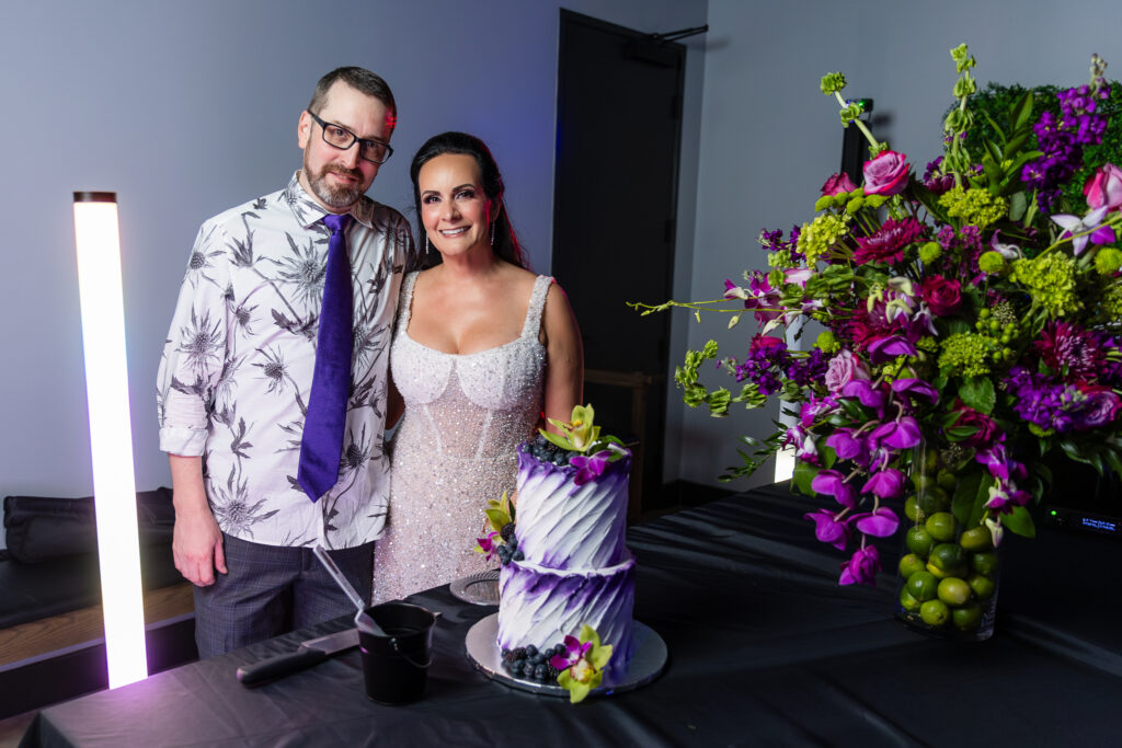 bride and groom smiling with The London Baker white and purple 2-tier wedding cake