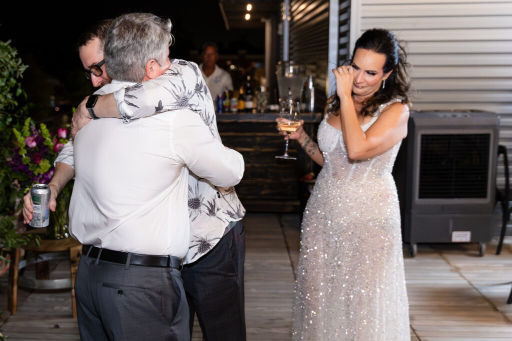 best man giving groom a hug after speech while bride wipes tear