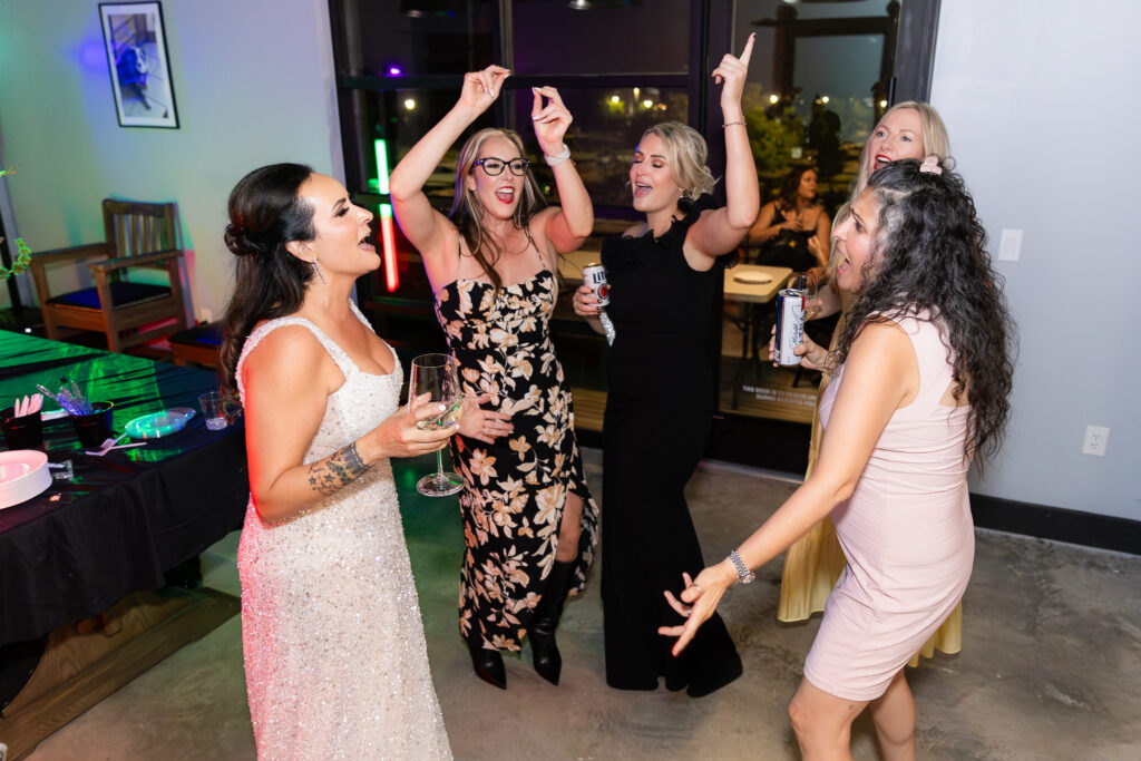 bride and friends dancing with arms up during wedding reception