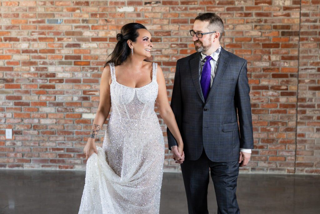 bride in a Galia Lahav Oriana sparkling a-line wedding dress smiling with groom in dark grey ted baker suit smiling at each other