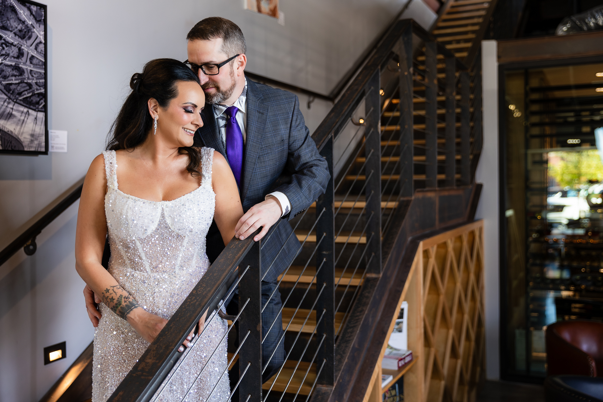 bride in a Galia Lahav Oriana sparkling a-line wedding dress standing on staircase at Prosper Wine House with groom in dark grey ted baker suit smiling into each other