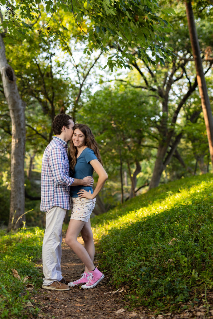 engaged man whispering into fiancée's ear while she laughs at Prather Park