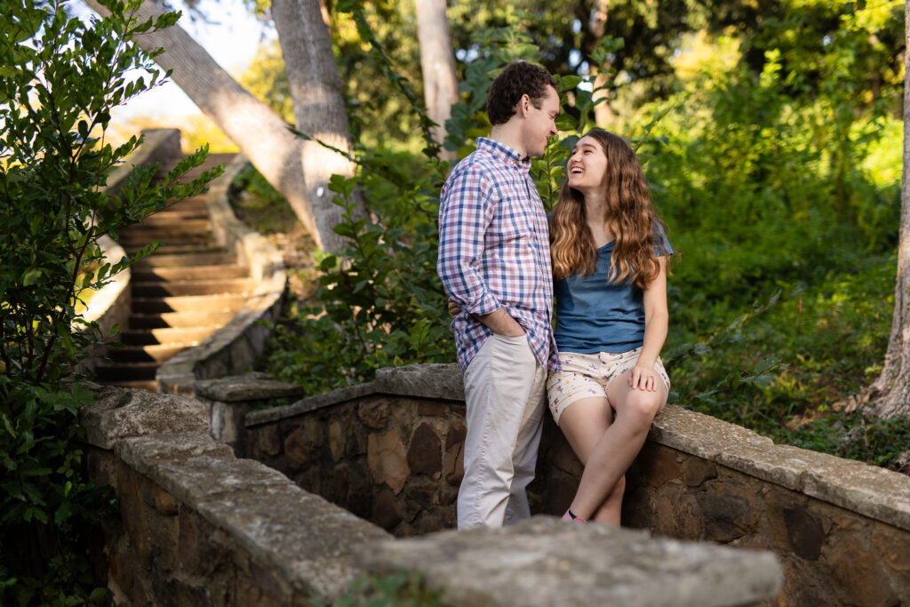 engaged couple laughing on stone bridge in Prather Park during engagement session