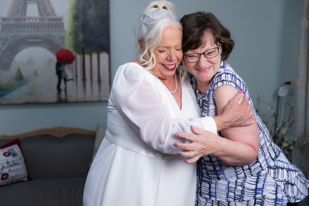 bride hugging friend smiling in The Abbey's bridal suite