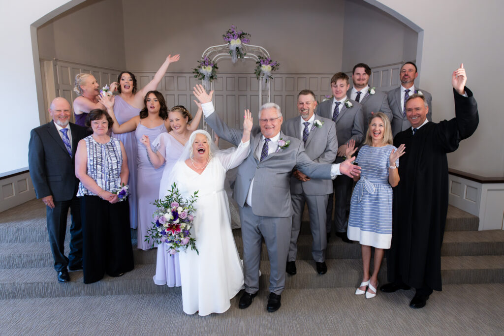 bride and groom cheering at the altar with friends and family during 50th vow renewal at The Abbey wedding venue in Justin TX