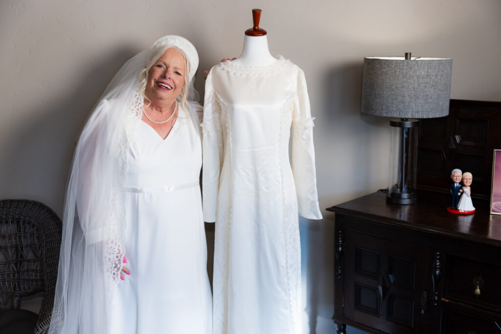 bride wearing wedding gown and original handmade wedding veil posing next to her original handmade wedding dress from 1974