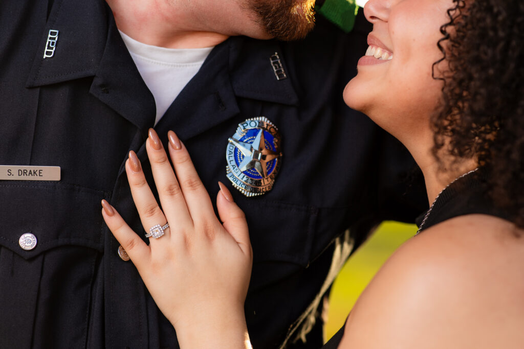 close up of hand and engagement ring with police badge on man's chest