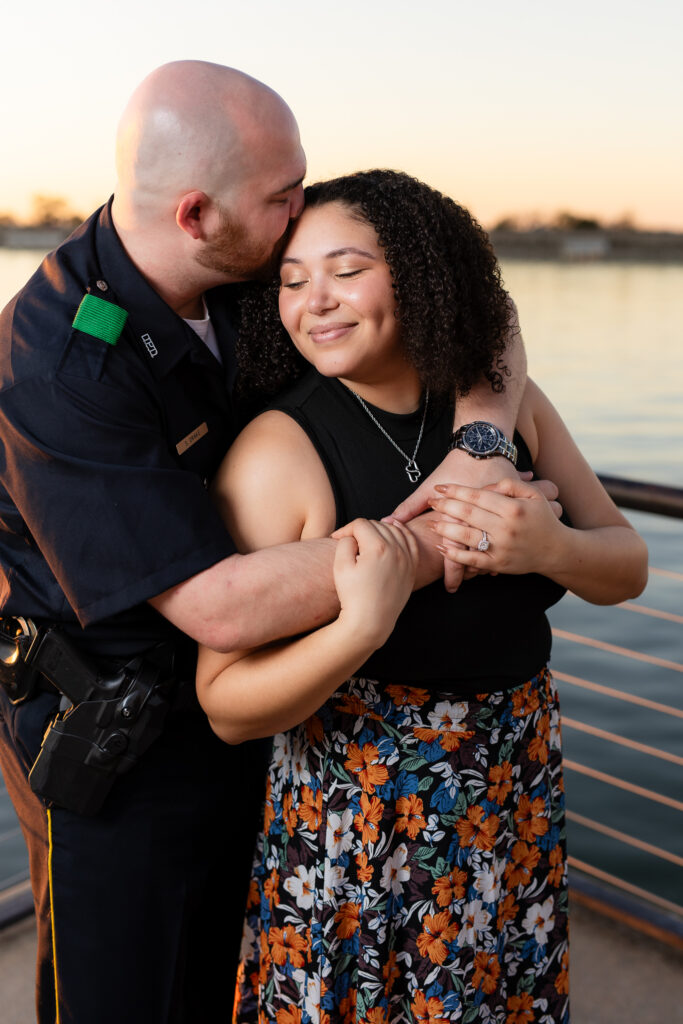 man kissing woman on temple while hugging her from behind and smiling