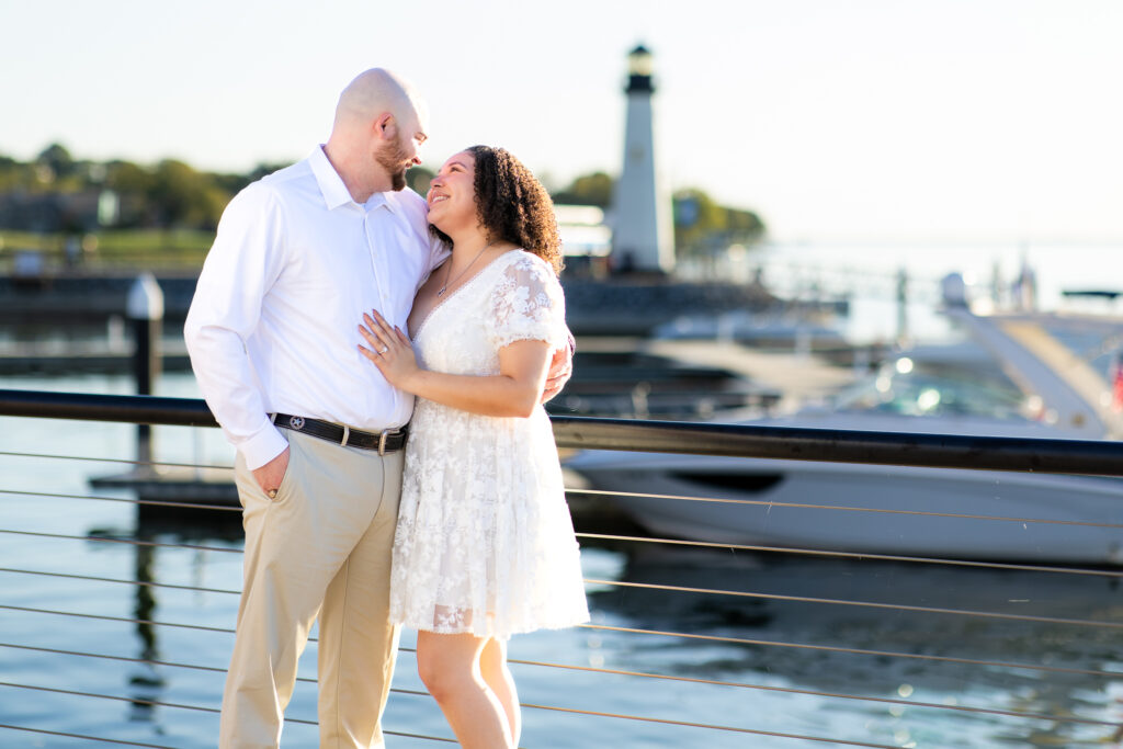 engaged couple wearing all white looking lovingly into each other's eyes by Rockwall lake with lighthouse in background