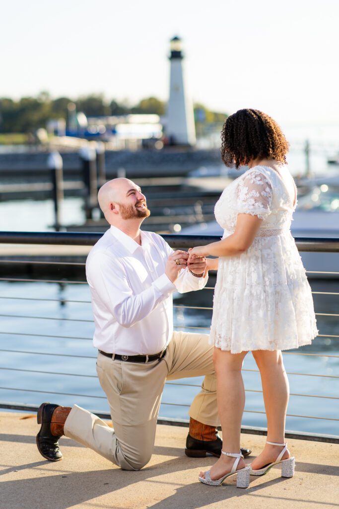 man proposing by Rockwall lake with lighthouse in background