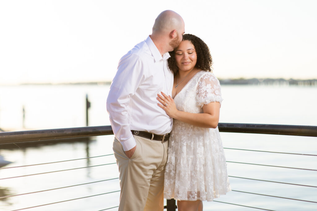 Man kissing fiancée on forehead at Rockwall lake during engagement session