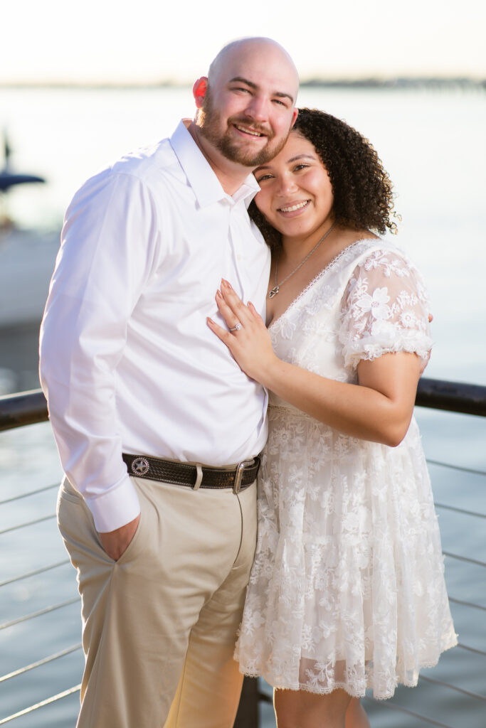 engaged couple in all white cuddling and smiling at Rockwall lake